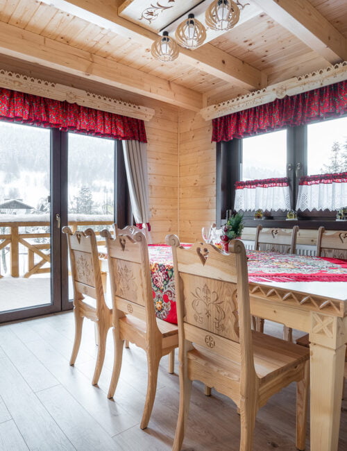 Widok na góralski stół z drzwiami balkonowymi prowadzącymi do ogrodu.