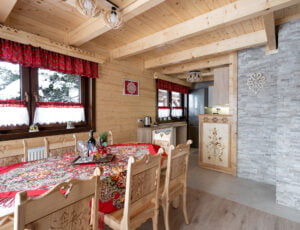 Jadalnia z widokiem na kuchnię, duży drewniany góralski stół z ozdobnymi krzesłami.