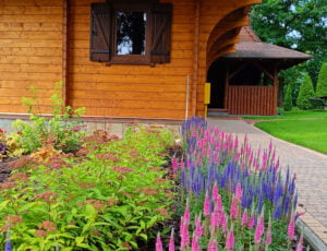 Widok na domek od boku z kolorowymi kwiatami.