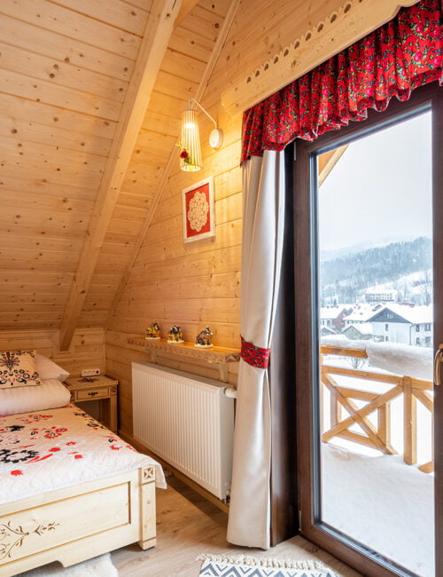 Sypialnia z pięknym łóżkiem małżeńskim z drewna, dużymi drzwiami balkonowymi i widokiem na Skrzyczne.