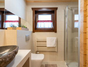 Jasna łazienka z dodatkami drewnianymi, kabiną prysznicową i kamienną umywalką.