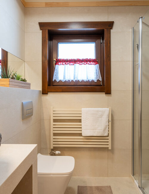 Jasna łazienka z dodatkami drewnianymi, kabiną prysznicową i kamienną umywalką.