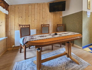 Elegancki salonik z wygodną kanapą, stołem oraz telewizorem, udekorowany boazerią, dodającą wyjątkowego uroku temu wnętrzu.