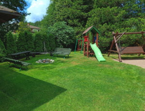 Miejsce na ognisko z huśtawką, zjeżdżalnią dla dzieci i trawą dookoła.