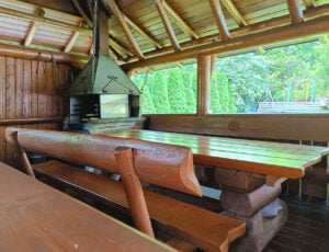 Góralski szałas z dużą ławą i rusztem do grillowania.