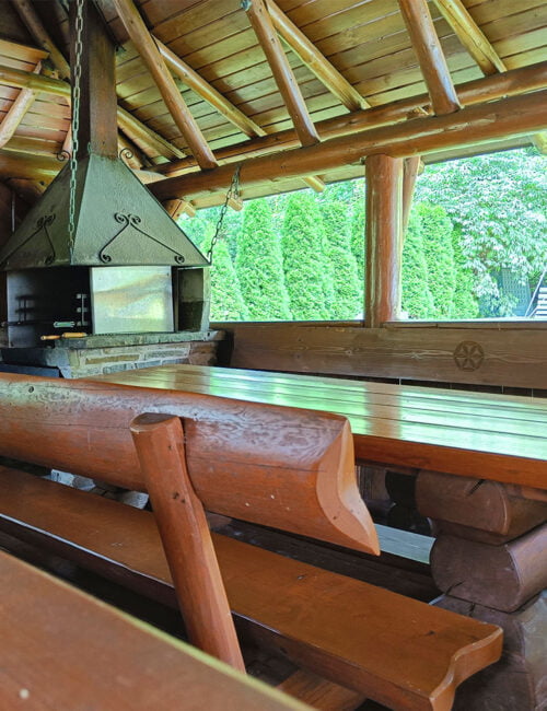 Góralski szałas z dużą ławą i rusztem do grillowania.