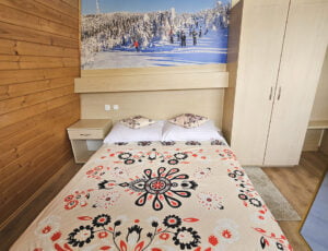 Przytulna sypialnia w kremowych tonacjach z boazerią, łóżkiem małżeńskim, szafą i obrazem zimowym ze Skrzycznego