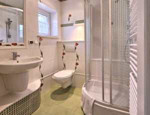 Jasna łazienka z tulipanami na ścianach, wyposażona w kabinę prysznicową, umywalkę, toaletę, suszarkę oraz ręczniki