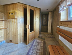Widok na całe pomieszczenie sauny w Willi Rosa, z wejściem, ławką i prysznicem, idealne dla gości szukających noclegów z wellness.