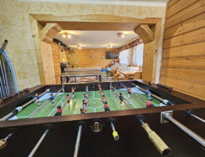 Duże, solidne piłkarzyki do gry na świetlicy, w tle drewniane ławki i stół do ping ponga.