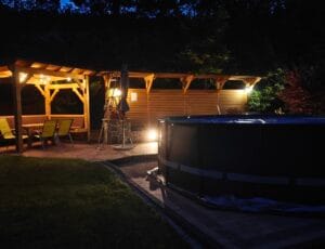 Podgrzewany basen ogrodowy nocą z oświetloną altaną w tle