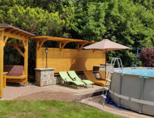 Basen z zadaszoną altanką, leżakami i ozdobną drewnianą ścianką w ogrodzie Willi Rosa, idealny na noclegi w Szczyrku.