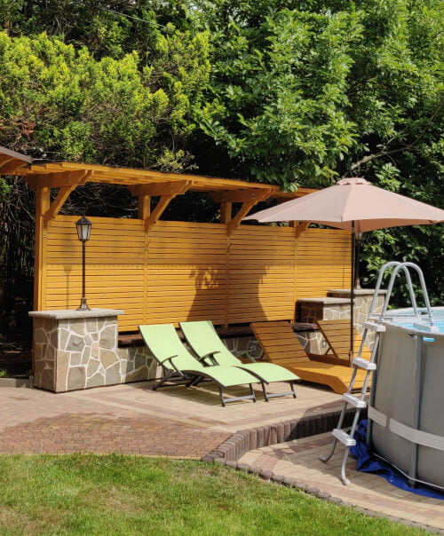 Basen z zadaszoną altanką, leżakami i ozdobną drewnianą ścianką w ogrodzie Willi Rosa, idealny na noclegi w Szczyrku.