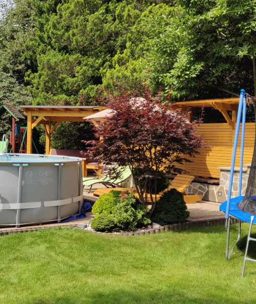 Basen i trampolina w ogrodzie Willi Rosa, z zadaszoną altanką i ozdobną drewnianą ścianką, idealne miejsce na noclegi w Szczyrku.