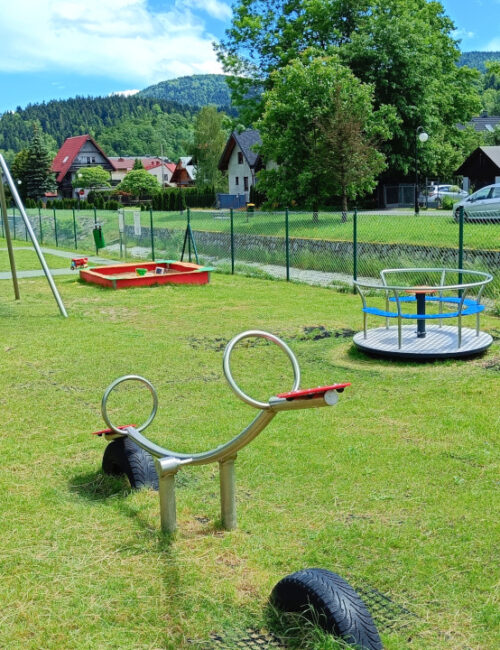 Urocze zdjęcie z małą karuzelą i konikiem - radosna zabawa dla najmłodszych, tuż obok naszego obiektu.