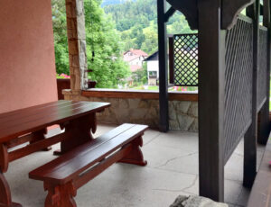 Taras z dużym stołem i dwoma ławkami, widok na góry i ogród